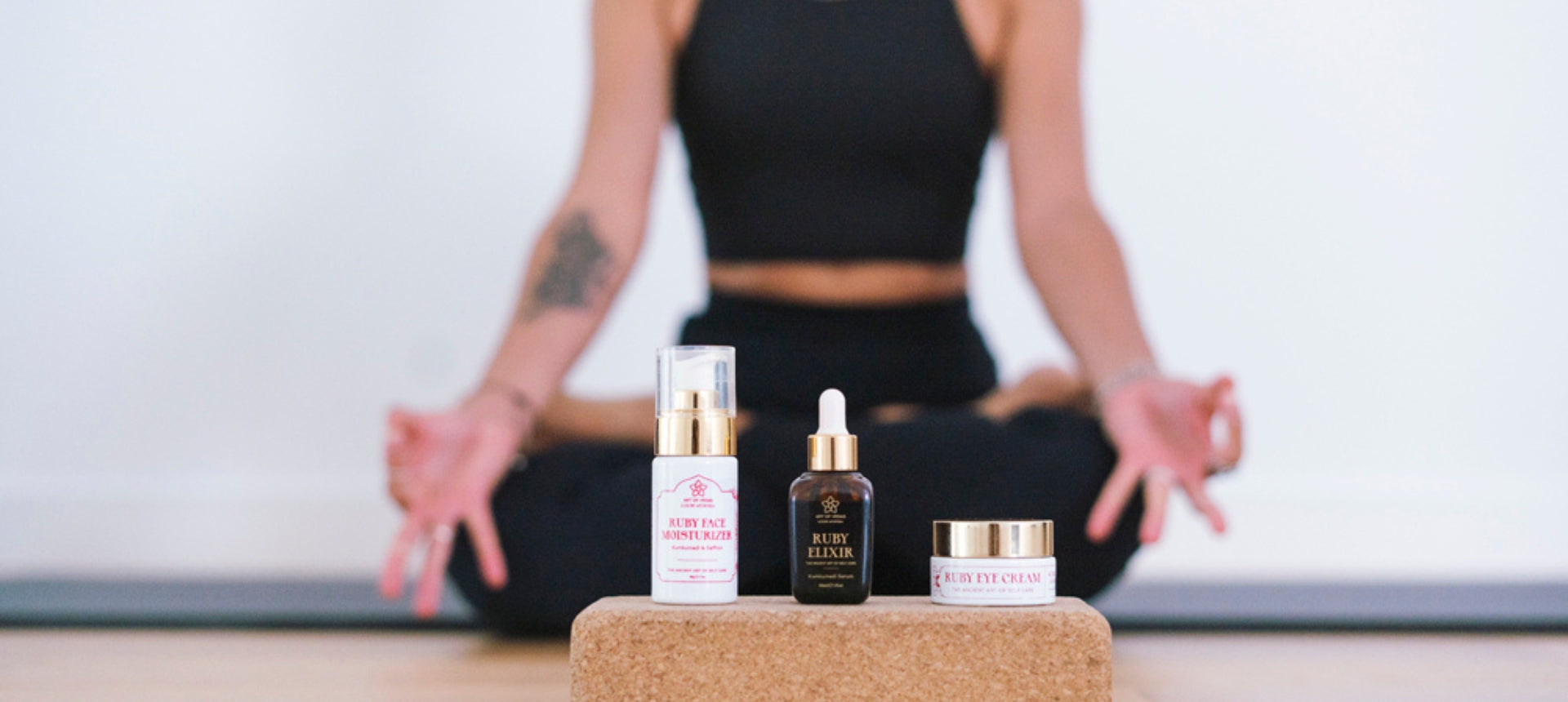 Art of Vedas partner program - Ruby Kumkumadi skincare collection with Face Moisturizer, Ruby Elixir serum, and Eye Cream on yoga block with wellness lifestyle background